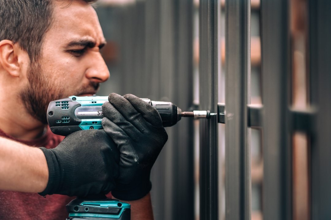 Construction worker using an cordless screwdriver for intalling metal elements